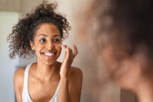 Skin care products that don't mix. Woman looking into her bathroom mirror applying eye cream.